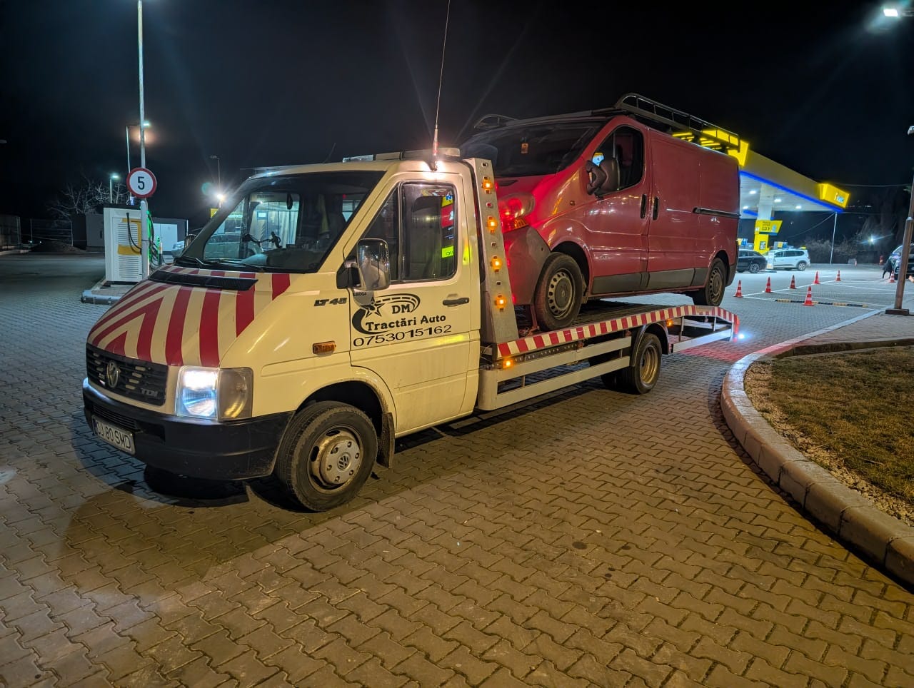 Transport pe platformă al unui autoturism roșu, seara